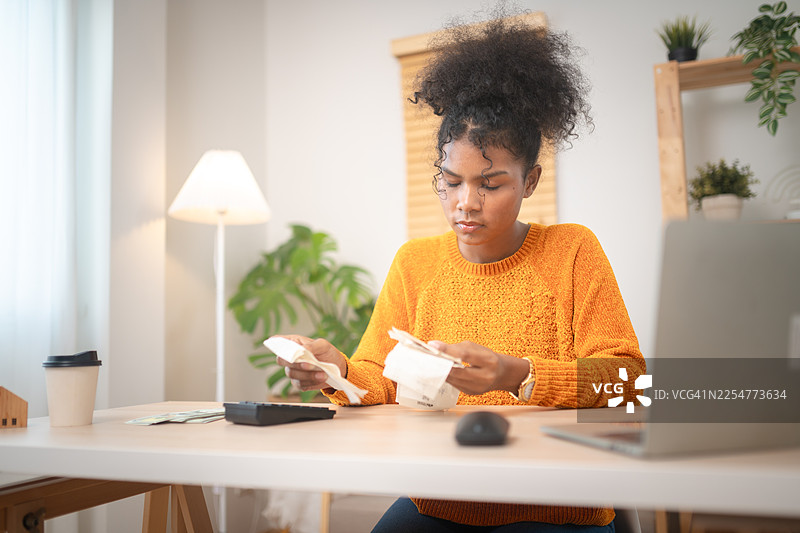年轻女子在家中的办公桌上管理财务；为个人财务成功进行预算、财务规划和税务准备。图片素材