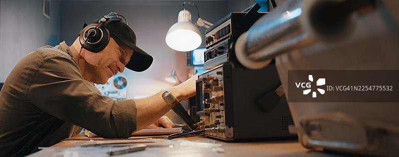 安全房间内的无线电设备。一名戴着耳机的操作员正在录音机上收听广播，并与笔记进行比对。军事间谍调查。图片素材