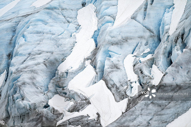 阿拉斯加肯纳半岛出口冰川的蓝色崎岖冰川，有冰裂缝和积雪，细节图片素材