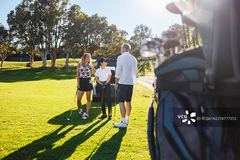 阳光明媚的球场上，多元化的情侣们正准备开始一场高尔夫球赛图片素材