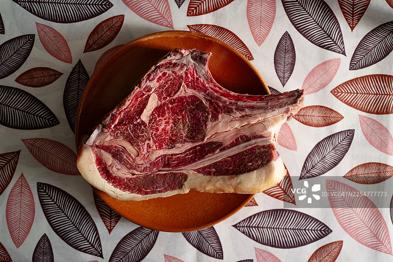 陶瓷盘上的生肋眼牛肉牛排，带有雪花纹，已准备好烹饪图片素材