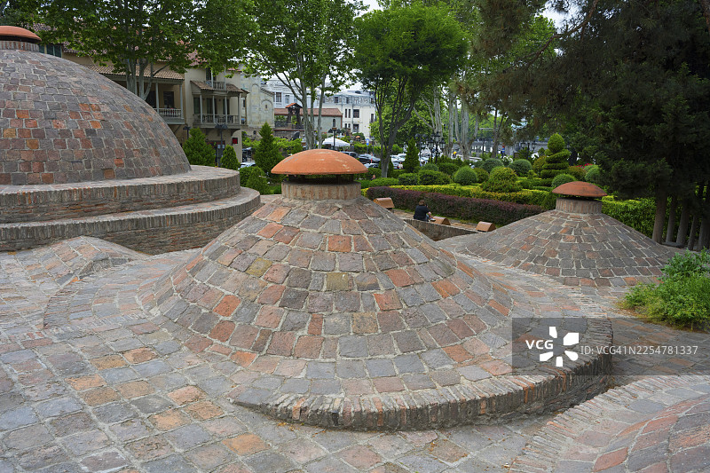 硫磺浴场阿巴诺图巴尼温泉区，老城区，第比利斯，格鲁吉亚，带有经典砖砌元素的穹顶建筑和绿色环境图片素材