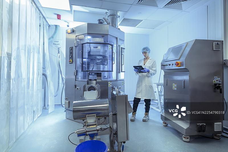 药厂工人使用平板电脑操作压片机图片素材