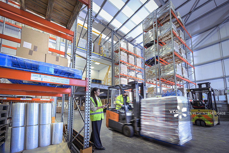 在制药厂仓库中，叉车运送着成品。图片素材