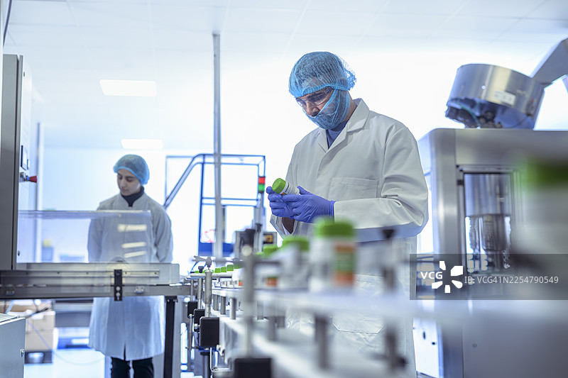 制药厂包装线上，工人正在检查药品药瓶图片素材
