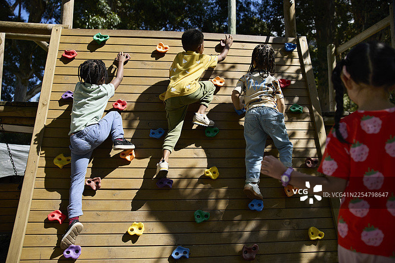 男孩们在学校操场上爬木墙图片素材
