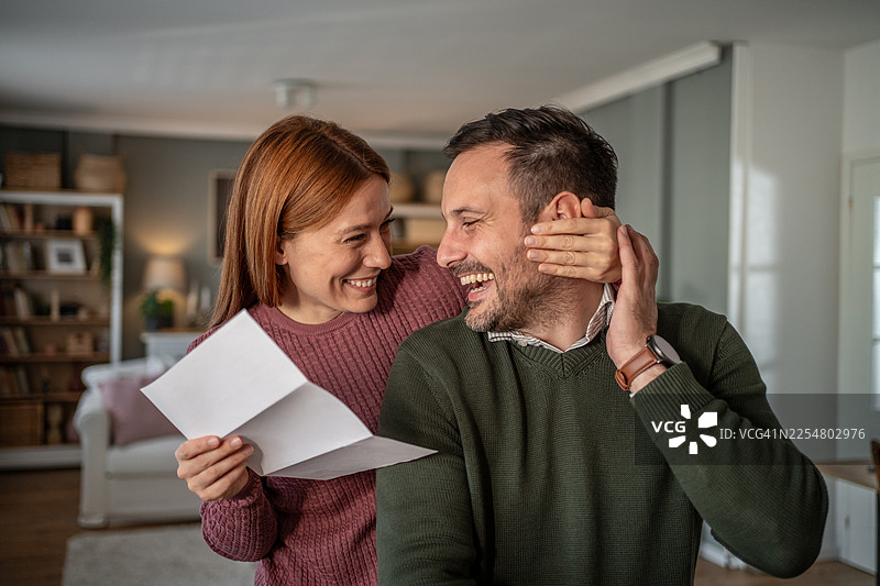 一对快乐的夫妇在家中收到惊喜消息，开怀大笑图片素材