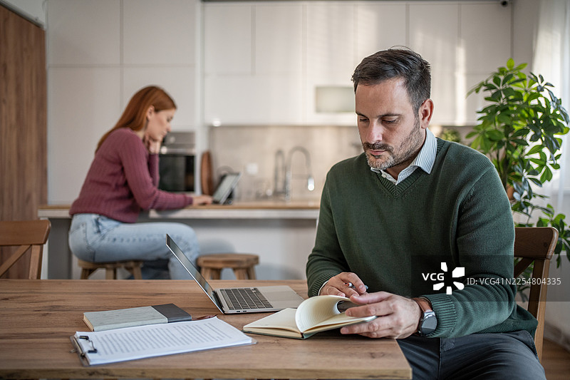 情侣在家通过笔记本电脑和记事本远程工作图片素材