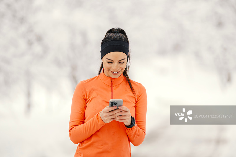 女人在冬天用智能手机查看健身应用图片素材