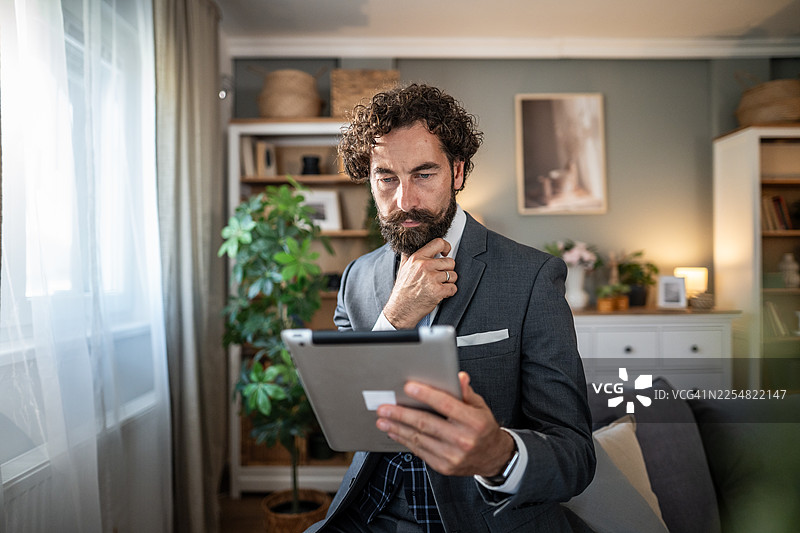 在家中办公室使用平板电脑工作的思考中的男人图片素材