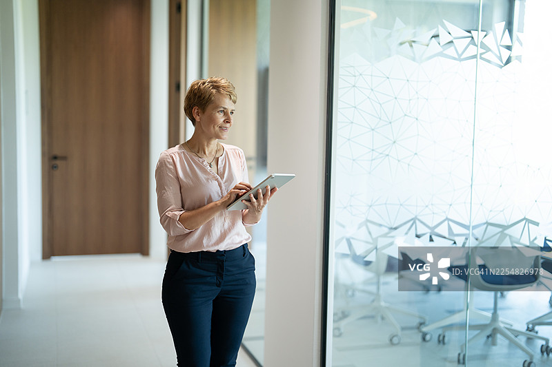 女商人正在现代办公室走廊使用数字平板电脑图片素材
