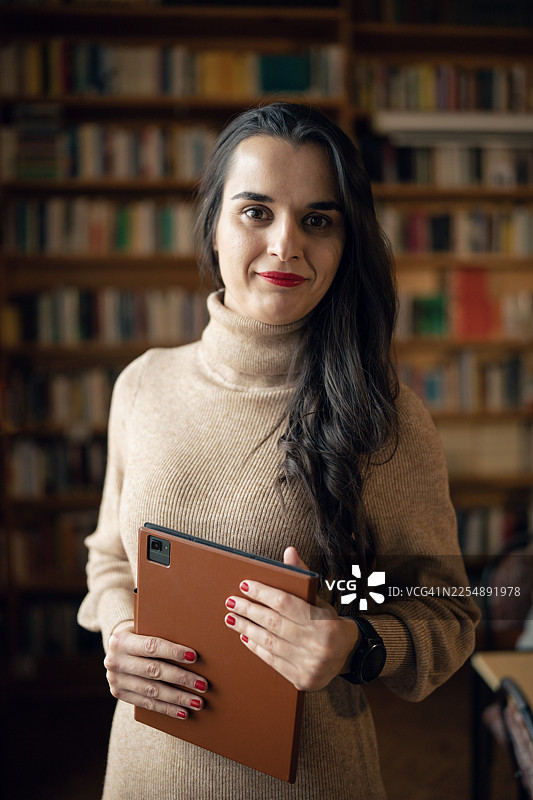 女图书管理员在图书馆里使用平板电脑。图片素材