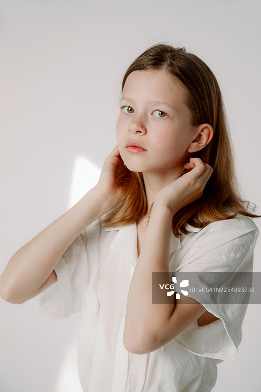 身穿白衬衫的年轻女孩肖像，柔和的自然光线，沉思的表情图片素材