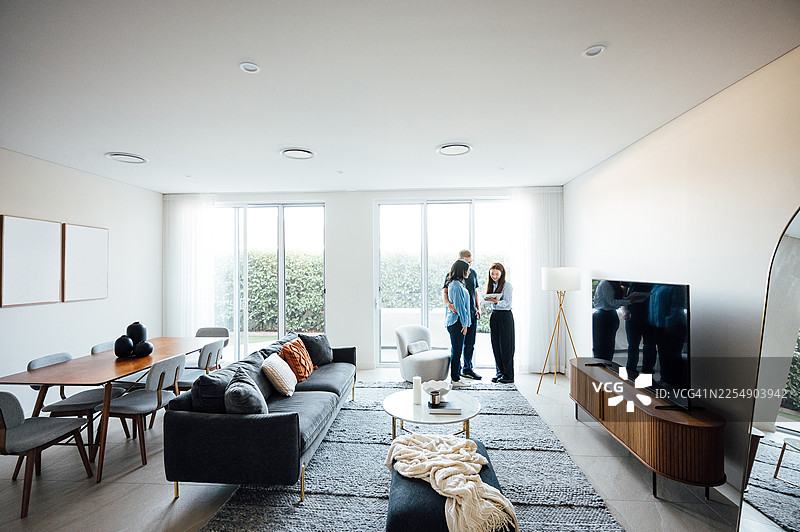一对成年夫妇在购买房产。房地产经纪人正在与一对已婚夫妇交谈，并向他们展示明亮的现代公寓图片素材