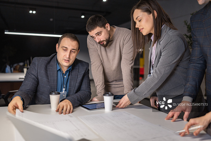 一群多元化的专业人士在现代办公室里合作处理文件图片素材