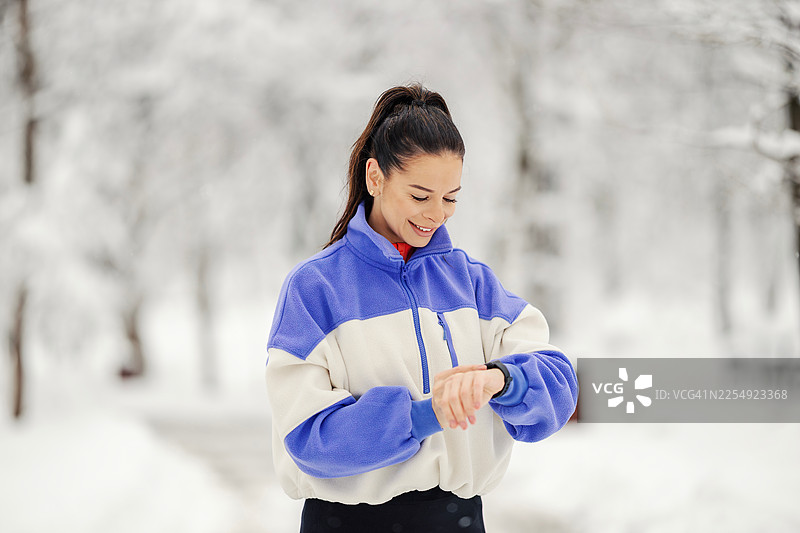 女性在冬季健身活动中查看智能手表图片素材