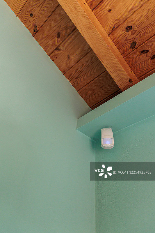 木制天花板下的运动传感器，灯亮着图片素材