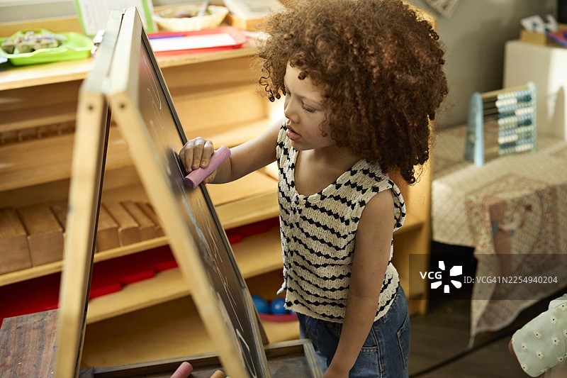 女孩在教室的黑板上写字图片素材