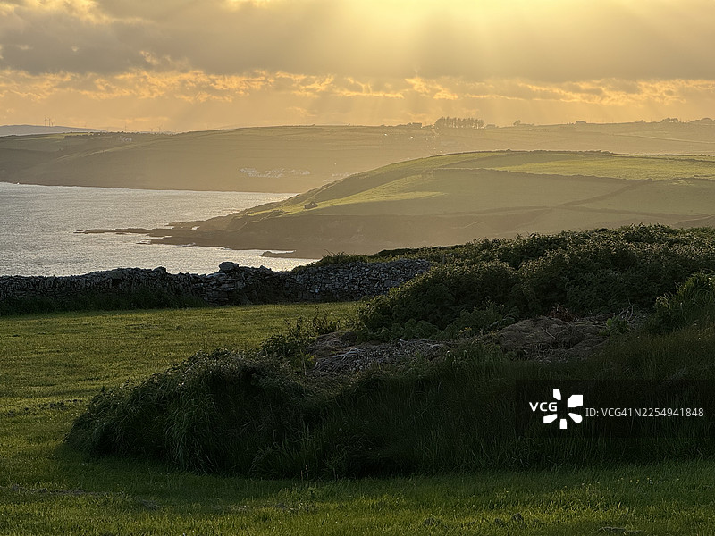 爱尔兰科克郡克洛纳基尔蒂，狂野大西洋之路因奇多尼湾上空阴沉的落日图片素材