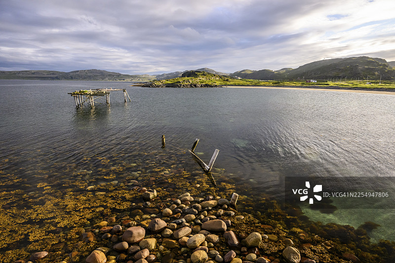 挪威芬马克郡孔斯峡湾韦德内斯，林地岛屿旁平静湖水中的木质栈道遗址图片素材