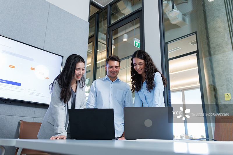 多元化的商务团队协作，在现代办公室会议室里，同事们正在讨论项目计划和商业策略，他们都使用笔记本电脑。图片素材