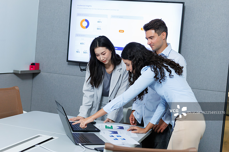 多元化的同事们在办公室会议上讨论商业计划，并在笔记本电脑上审阅数据。图片素材