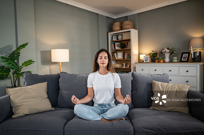年轻女子在家舒适的沙发上冥想图片素材