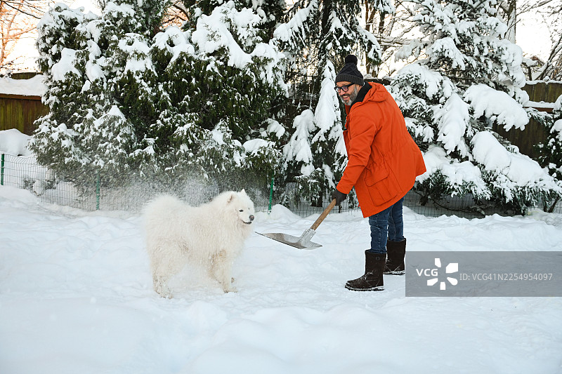 一位成熟的成年男子正在花园里铲雪图片素材