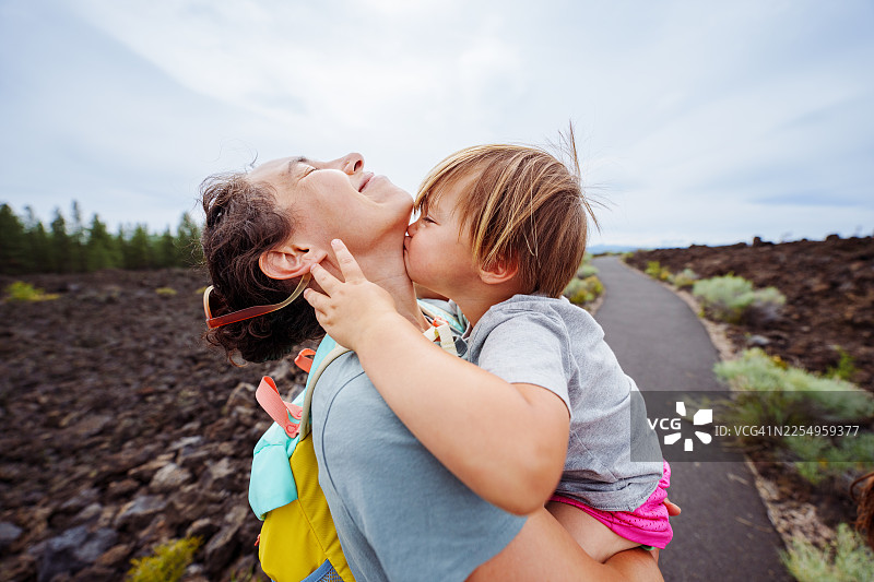 小男孩在户外徒步时亲吻他的妈妈图片素材