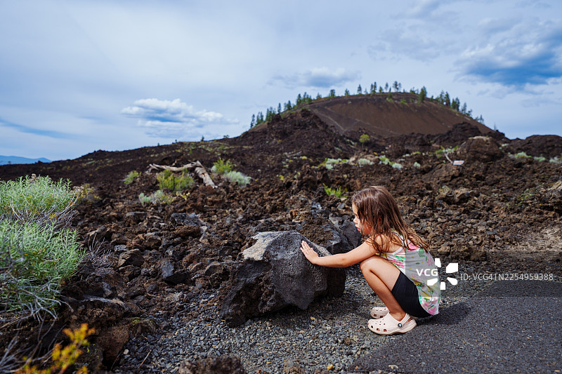 小女孩在家庭自然徒步中感受熔岩石的纹理图片素材