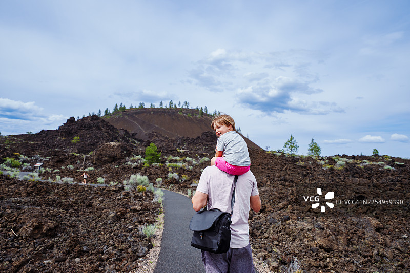 小男孩在户外徒步时骑在父亲的肩上图片素材