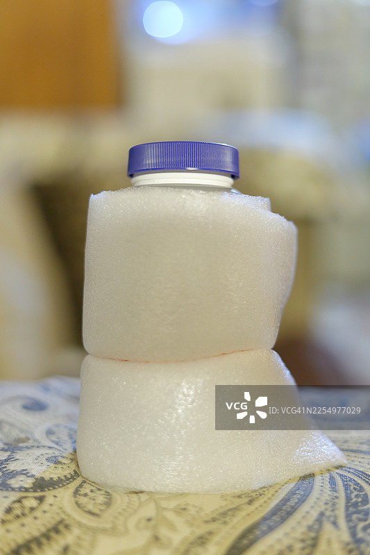 带蓝色瓶盖的瓶子，用蓬松的白色泡沫纸包裹以确保安全，准备发货。图片素材