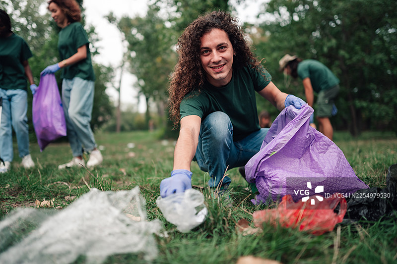 年轻男子与社区团体一起志愿清洁公园环境图片素材