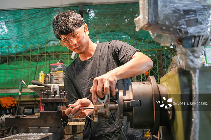 机械师在机械车间的工业环境中操作设备，动作镜头，专注环境图片素材