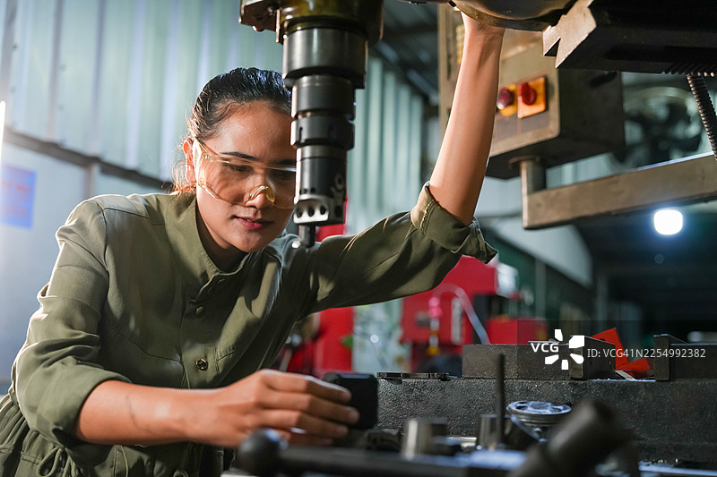 精湛的机械加工，技术娴熟的女操作员在工业车间，聚焦现代化工厂设备，特写镜头，赋权图片素材