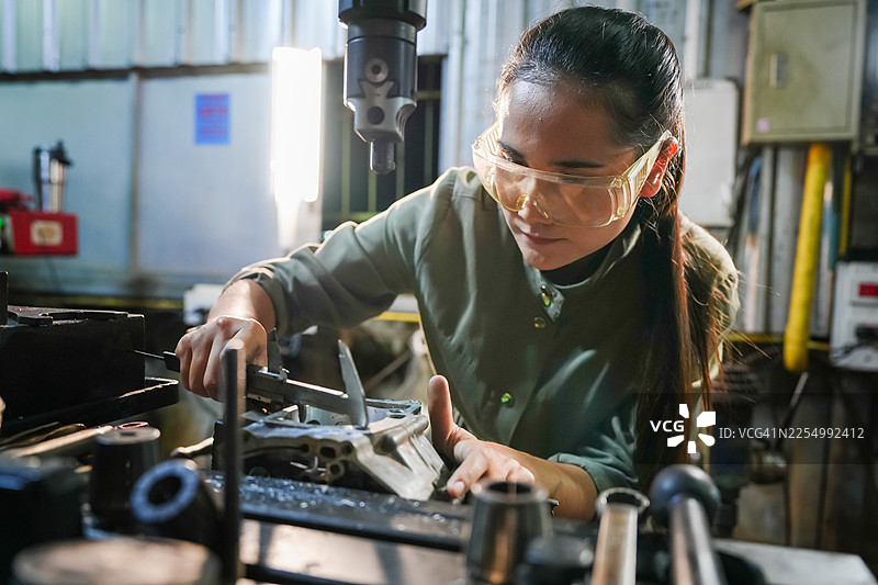 精密工程女技术员在机加工车间工作，工业环境，特写镜头，赋能STEM领域的女性图片素材