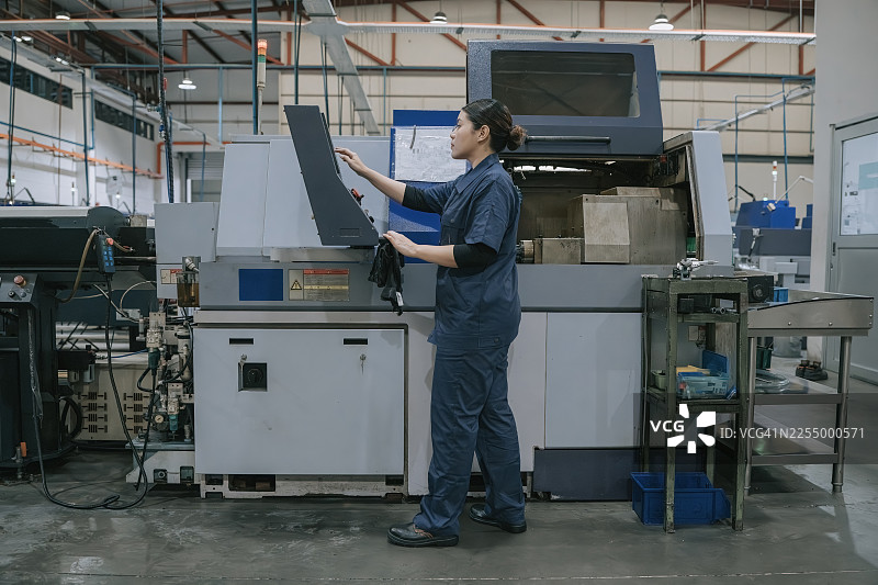 现代制造工厂里操作数控机床的亚洲女性工厂工人图片素材