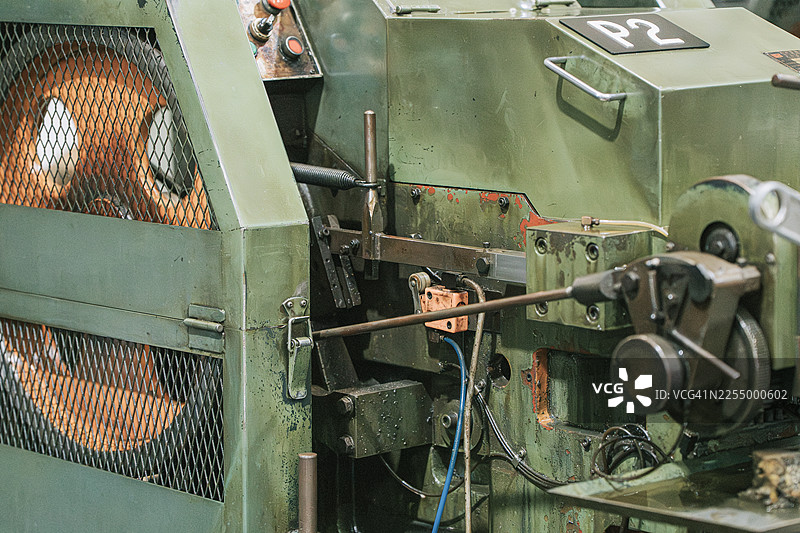 工厂里的机械式金属线材和金属棒成型机（带安全防护罩）图片素材