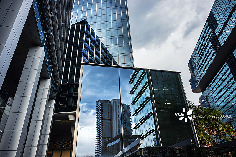 城市玻璃摩天大楼的倒影与雨云图片素材