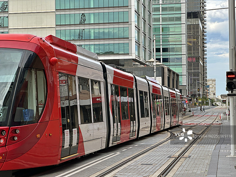 现代红色有轨电车行驶在城市街道上图片素材