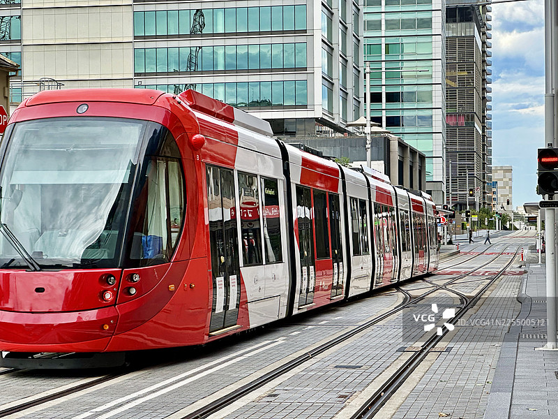 现代红色有轨电车行驶在城市街道上图片素材