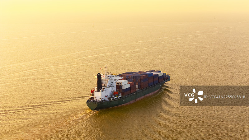 商务物流、进出口、航运或货运的空中视角集装箱货船，晨光中的金色光芒。图片素材