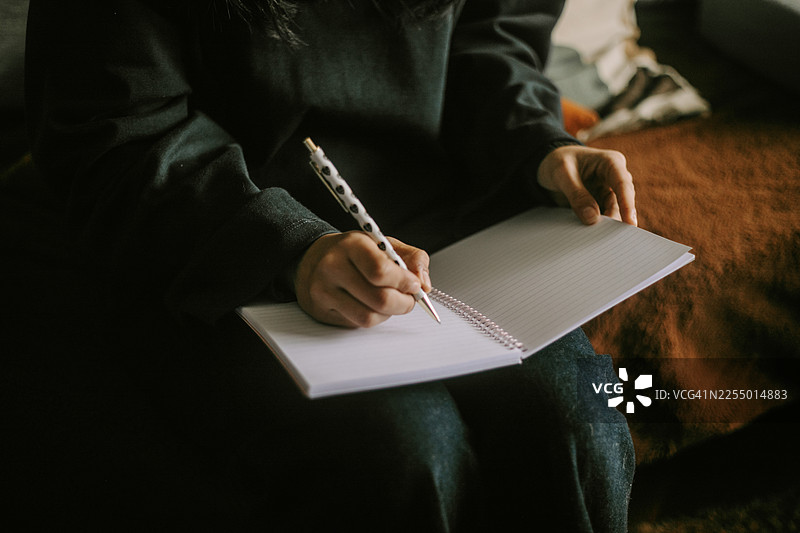 年轻女子在书桌前写日记，捕捉了日常生活平静而反思的瞬间。创意写作图片素材