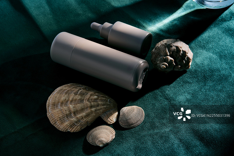 青绿色织物上带有天然海螺的护肤化妆品图片素材