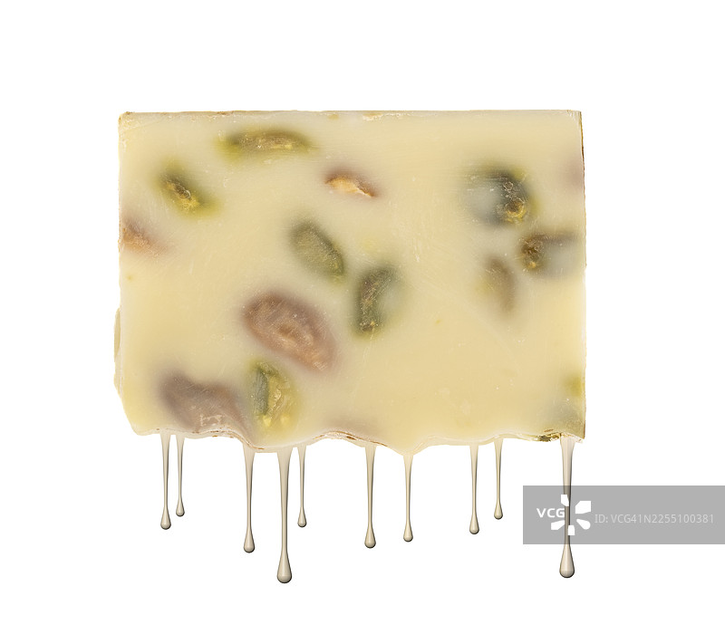 白色巧克力和开心果的特写，在高温下融化滴落，在白色背景下呈现剪影效果。图片素材