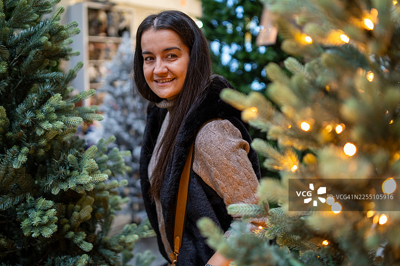 一位美丽的年轻女子在商店里挑选新年树图片素材