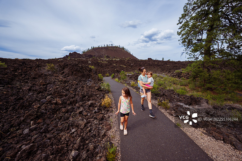 一家人在熔岩地貌徒步，远处是熔岩山图片素材