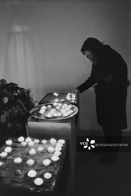 德国巴伐利亚州奥格斯堡的天主教教堂圣莫里茨。一名男子在纪念桌前点燃蜡烛，黑白场景图片素材