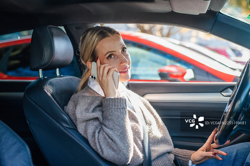 女子在车内打电话。城市通勤者。图片素材