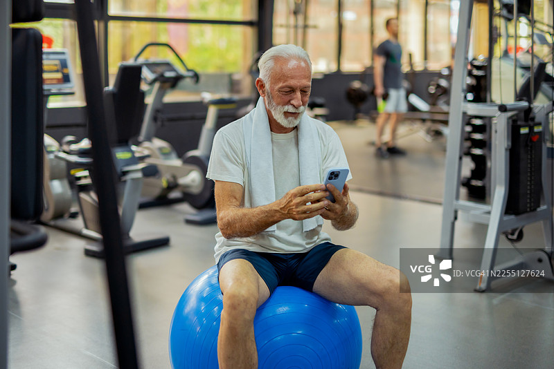 老年男性在健身中心跟随手机健身计划图片素材